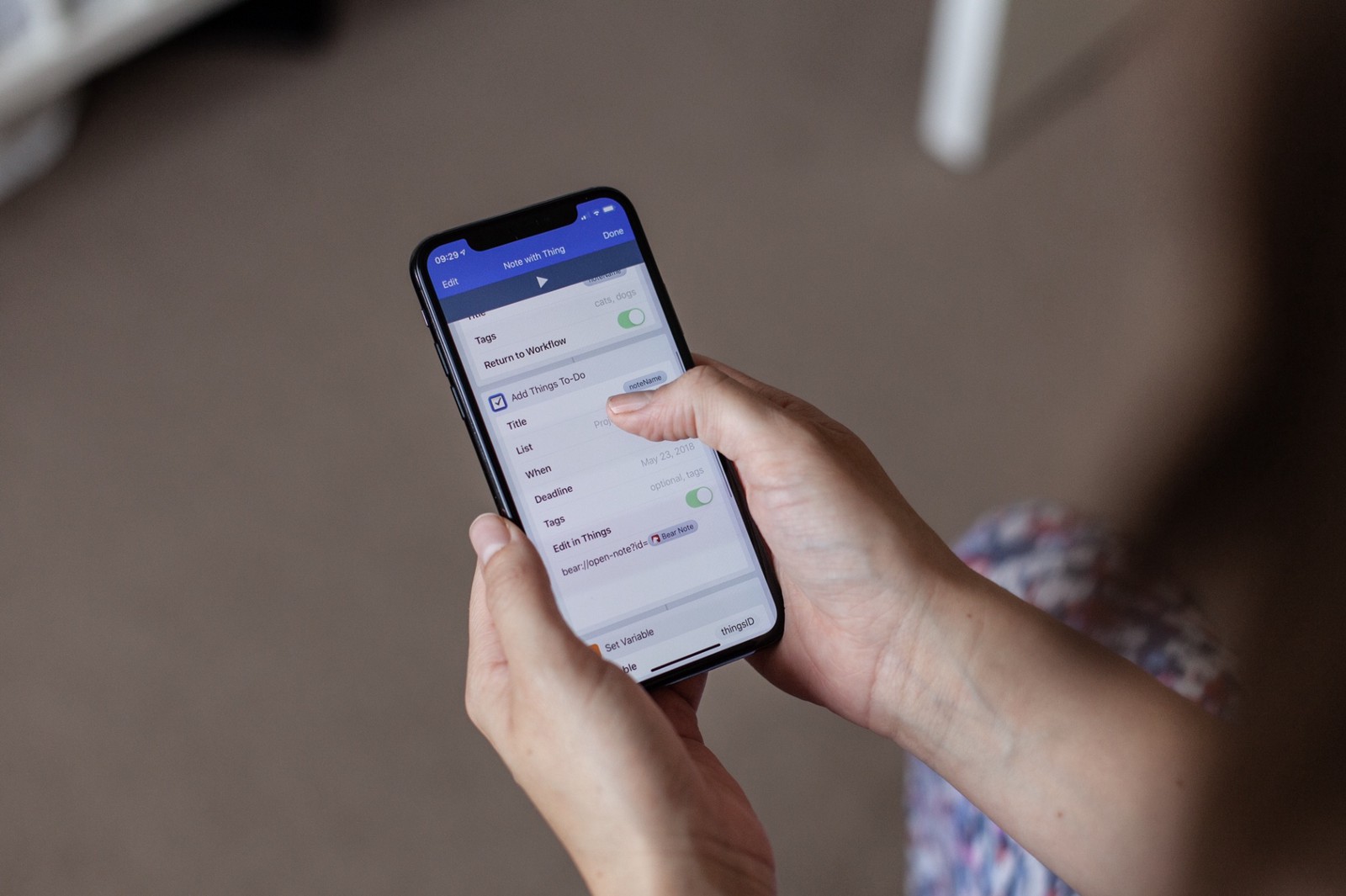 Woman's hands holding an iPhone X and pressing on a control on screen